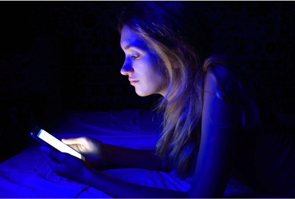 a girl holding a phone in her bed